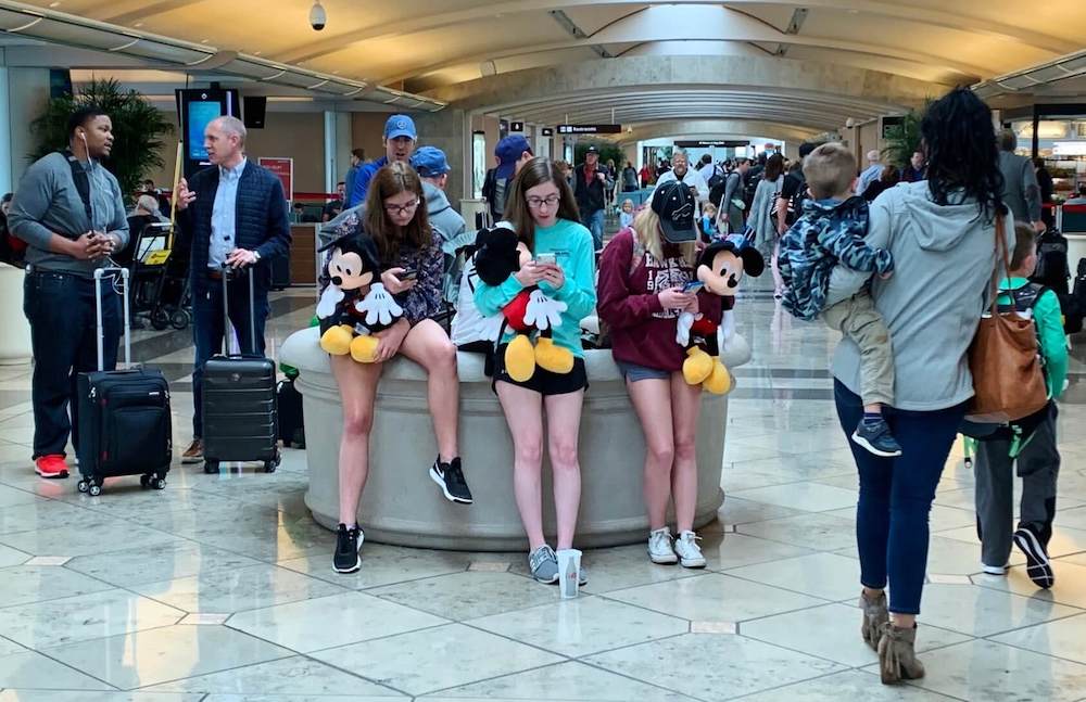 Image of three teens holding Mickey dolls at the Orlando Airport.